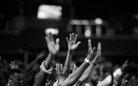 black and white photo of crowd with hands raised in worship